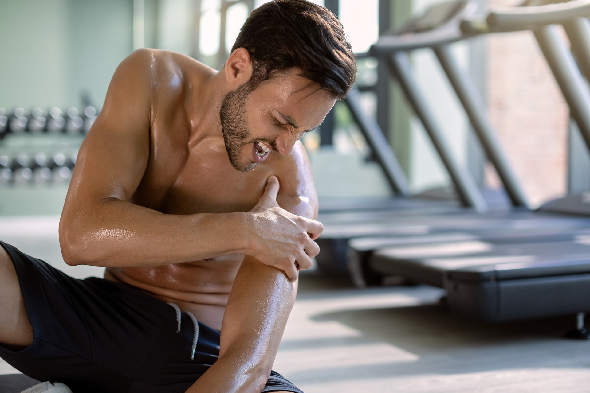 male athlete injured his shoulder during gym's workout.